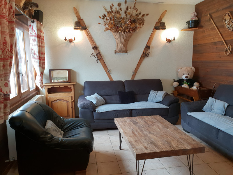 Coin salon décoré avec des vieux skis, raquettes, bâtons et ours en peluche