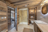 Salle de bains avec douche, toilettes, double vasque, miroir, murs et plafond en bois