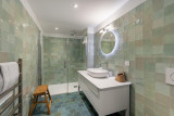 Salle de bains avec douche à l'tialtienne, vasque et meuble, miroir rond, briques de verre aux murs, sèche serviettes