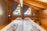Chambre avec deux lits simples, fenêtres, poutres apparentes