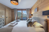 Chambre double avec grand lit, accès au balcon par une porte fenêtre, vue montagne
