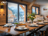 Salle à manger avec grande table dressée, baies vitrées donnant accès au balcon, vue sur les montagnes