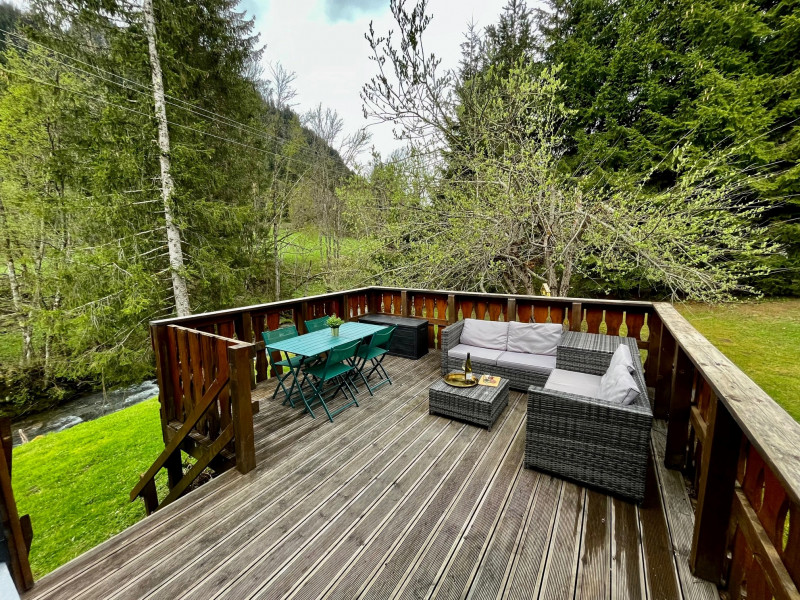 Grande terrasse avec coin salon et table à manger surplombant la rivière